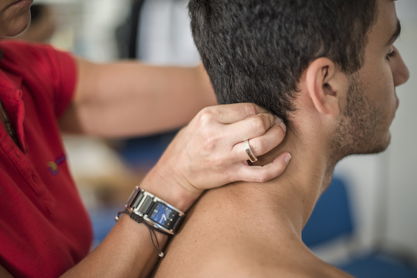fisioterapista massaggia giovane paziente per curare un dolore cervicale